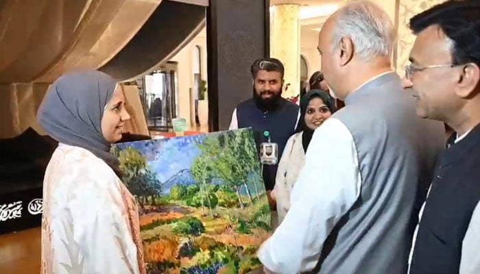 The envoy Faisal Niaz Tirmizi considers works of art during an exhibition to celebrate Pakistan Day. - Postpone
