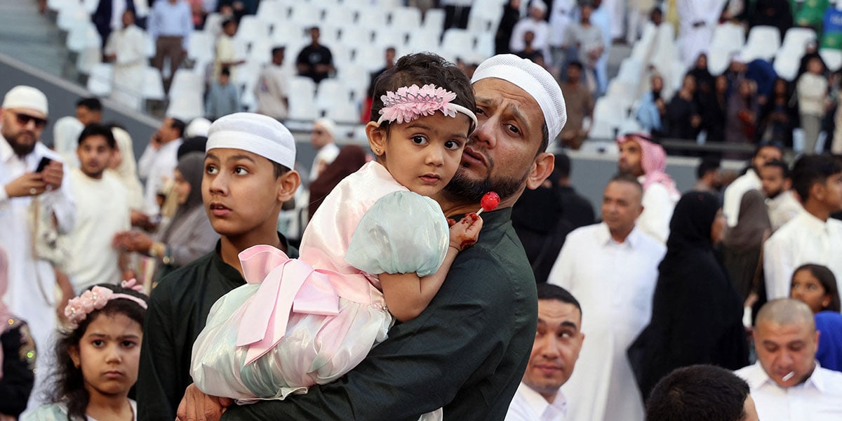 A man holds a child after playing Eid prayer at the education stadium in Al Rayyan, Qatar, March 30, 2025. - Reuters