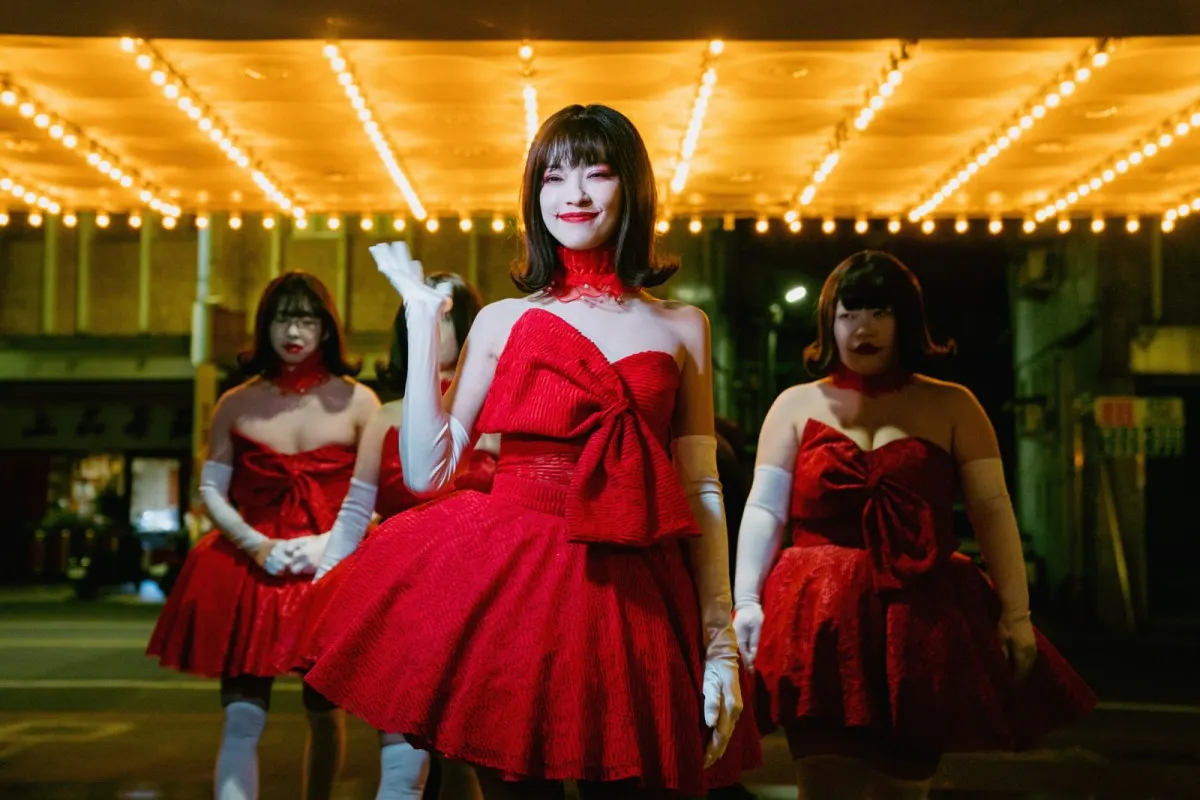 Three women in red dresses pose together