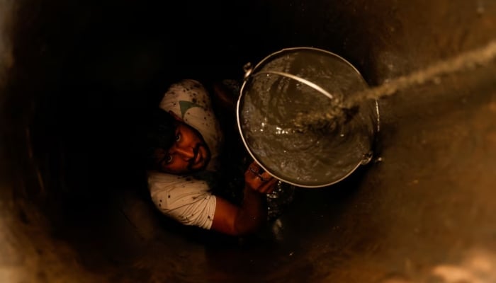 A man cleanses a small well in Chandrapur, India, February 3, 2025. - Reuters