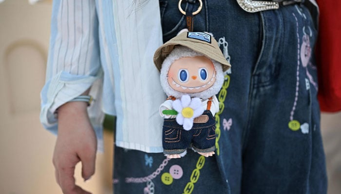 A woman with a figure of the character Labu as she Vistis Pop Mart Pop Land in Beijing, China, June 18, 2025. - AFP