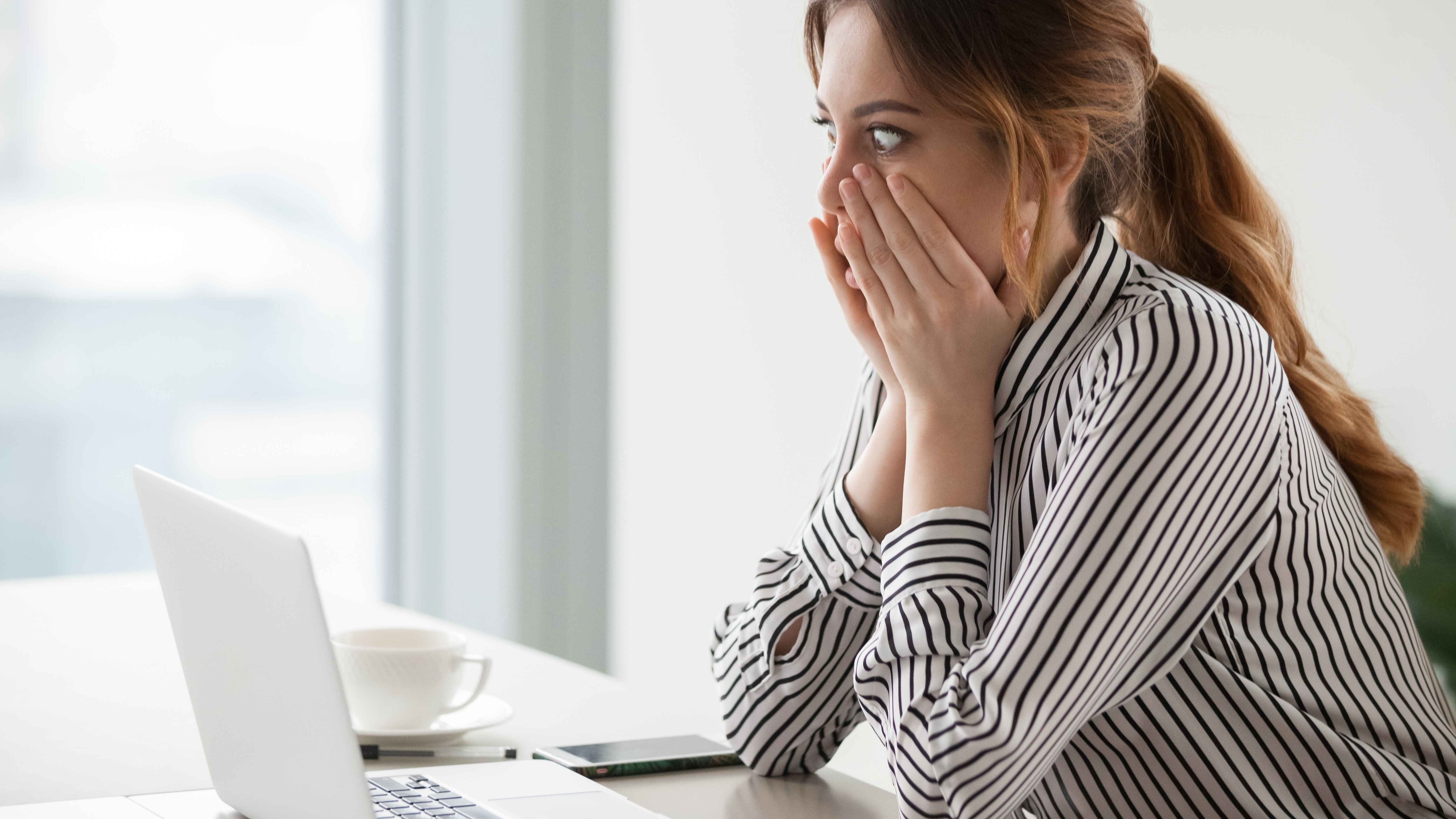 Shocked female worker looking at laptop screen