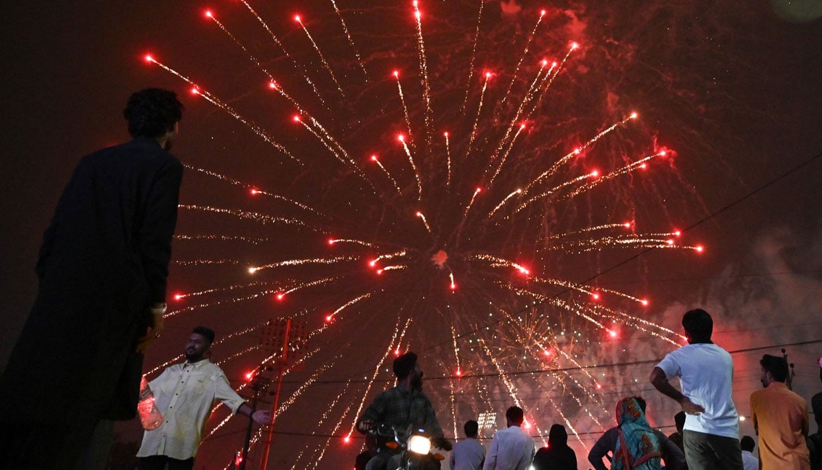 People watch a fireworks displayed in front of the national stadium during the celebrations of independence day in Karachi on August 14, 2025. - AFP