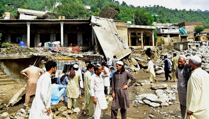 Residents come together in front of damaged houses after sudden floods in the Khyber Pakhtunkhwa Biner district on August 16, 2025. - AFP