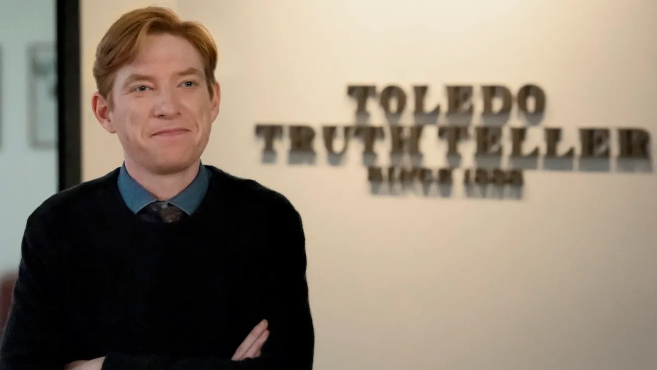 Domnhall Gleeson stands in front of a panel for the Toledo Truth Teller newspaper