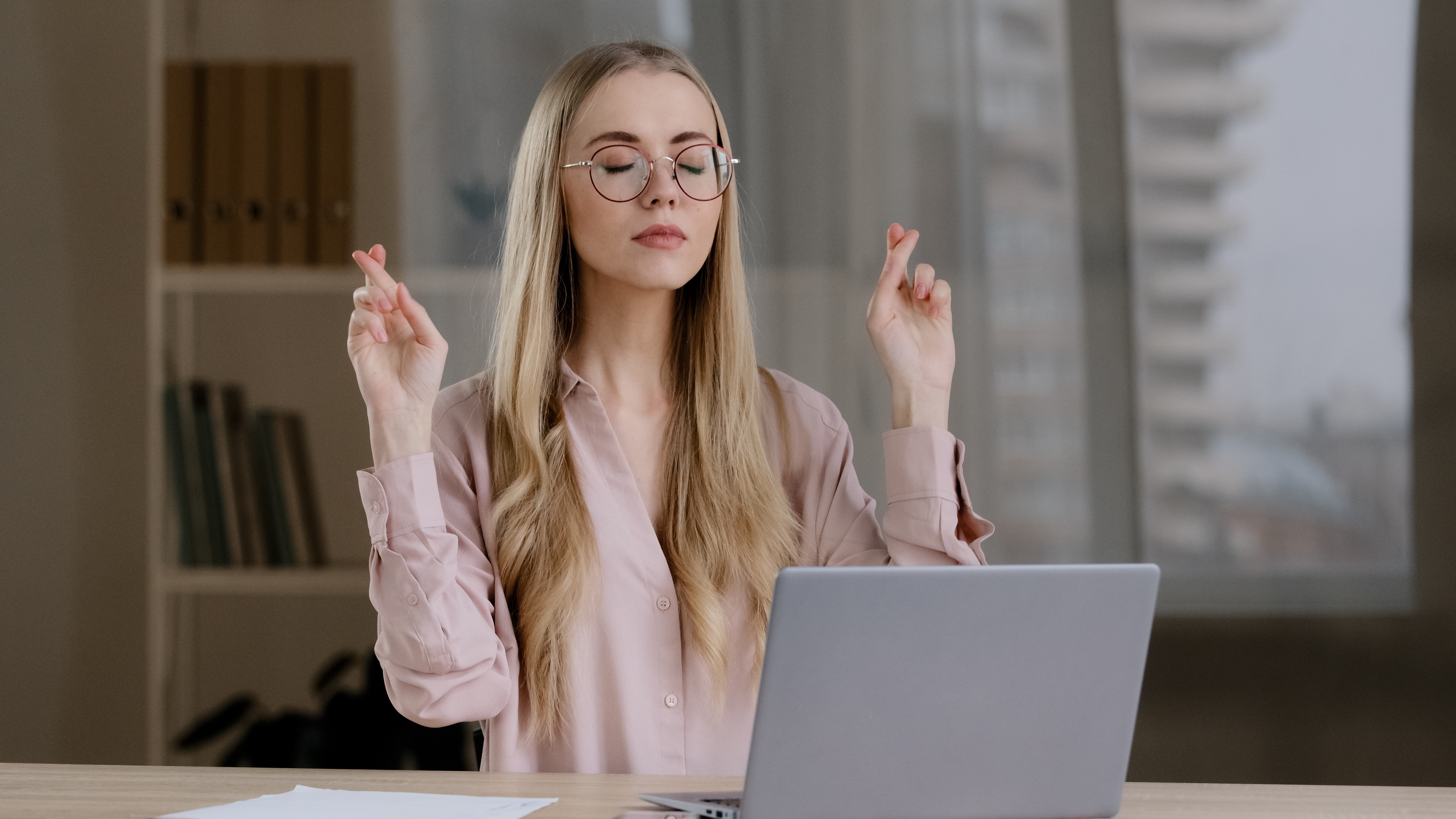 Girl using a laptop hoping for good luck with her crossed fingers