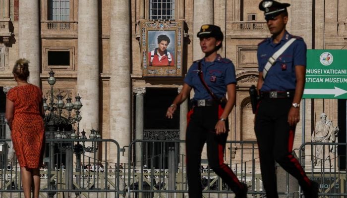 Carabinieri passes in front of a tapestry suspended from the facade of the Saint Peters basilica with the Vatican representing an image of Carlo Acutis, an Italian boy of British origin who will become the first millennium to be made a Saint Catholic during a ceremony led by Pope Leo, as we can see in Rome, Italy, September 4, 2025.