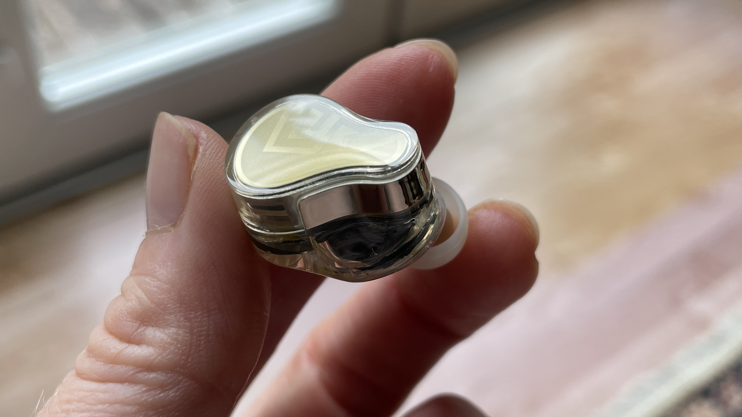 Soundpeats H3 headphones and the case held in one hand, in a living room