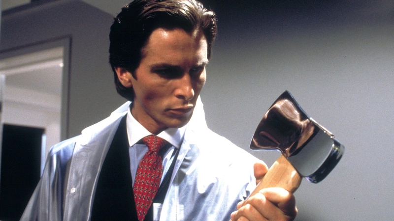 A calm of the American Psycho film in which Patrick Bateman (Christian Bale) carries a costume and looks at an ax.