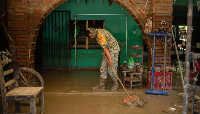 A Mexican army soldier works to remove mud from a house flooded by heavy rains in the municipality of Alamo, Veracruz, Mexico, October 12, 2025. — AFP
