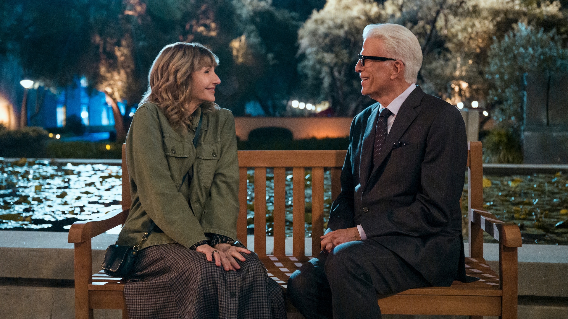 Charles and Mona sit on a bench and smile at each other in A Man on the Inside season 2