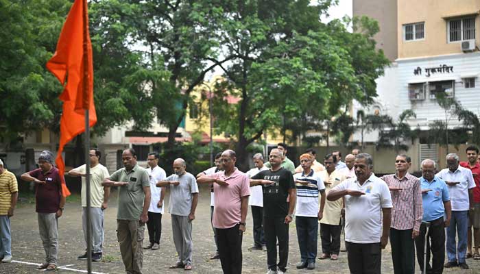 Rashtriya Swayamsevak Sangh (RSS) volunteers salute the organization's flag before morning exercises during a shakha, or training session, of the Hindu nationalist organization at a park in Nagpur on October 3, 2025. — AFP