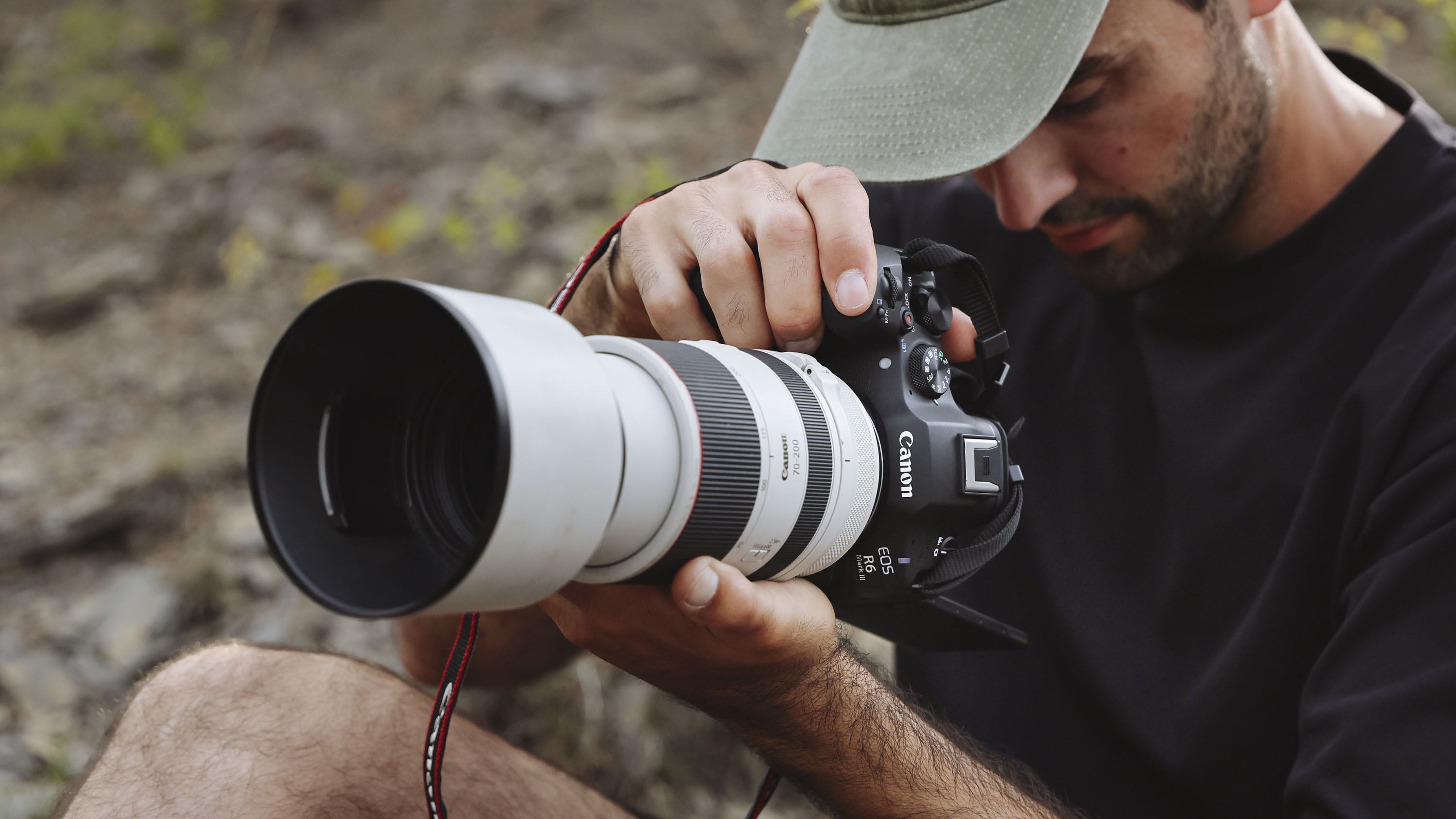 Canon EOS R6 Mark III camera with attached telephoto lens, held by male photographer in vertical orientation