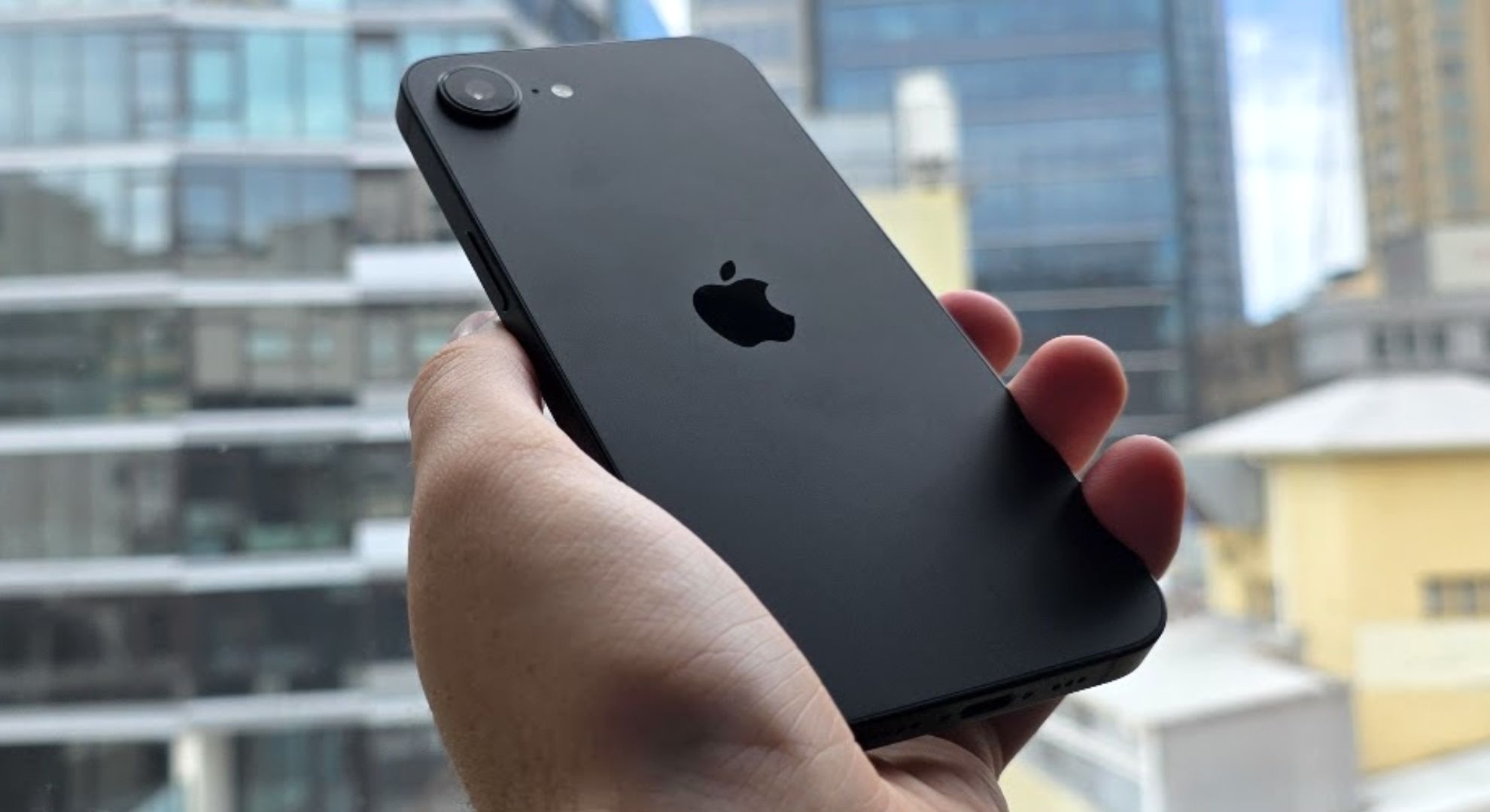 The Apple iPhone 16e held at an angle in front of a window