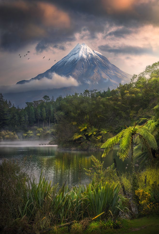 A snow-capped mountain with a tropical lake in the foreground