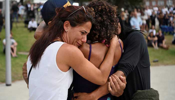 People hug each other as they visit a makeshift memorial after the attack on a Jewish party at Bondi Beach in Sydney, Australia, December 15, 2025. — Reuters