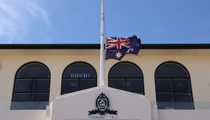 The Australian flag flies at half-mast at the Bondi Surf Bathers Life Saving Club near the Bondi Beach promenade, where mourners laid floral tributes to the victims of the December 14 shooting, in Sydney on December 18, 2025. — AFP