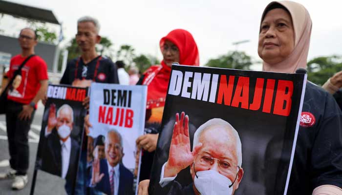 Supporters of former Malaysian Prime Minister Najib Razak hold banners depicting his portrait in front of the Palace of Justice, in Putrajaya, Malaysia, December 26, 2025. — Reuters