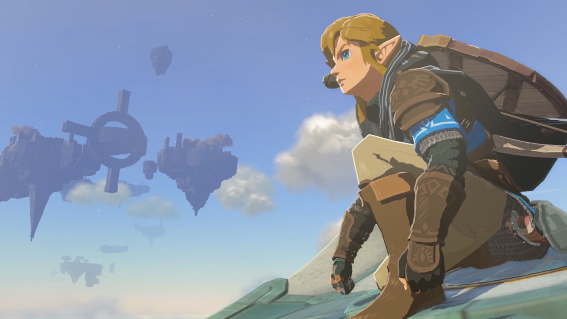 Link crouched down, looking at Hyrule. A sky island can be seen floating in the background