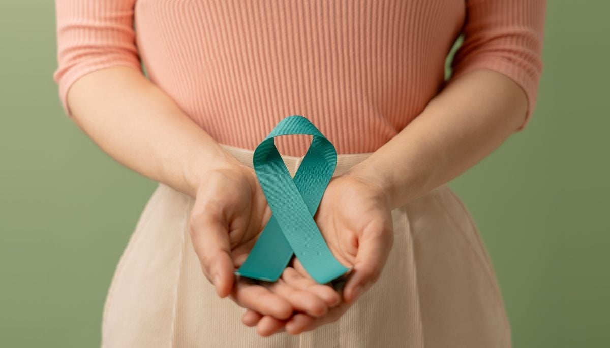 Representative image of a woman holding a teal colored ribbon indicating the cervical cancer awareness symbol. —Canva