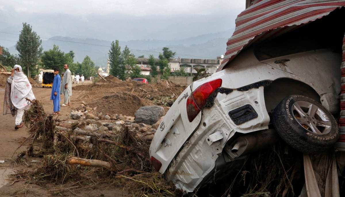 A woman walks past a damaged vehicle following heavy rain and flooding in Khyber Pakhtunkhwa's Buner district on August 16, 2025. — Reuters