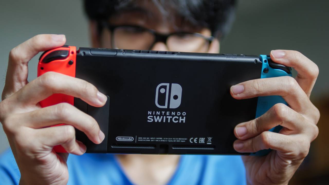 A person looking down and playing Nintendo Switch.