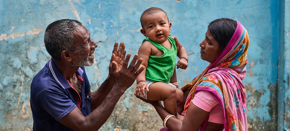 A baby is held by his mother and cared for by his grandfather at a community clinic in northern Bangladesh. 