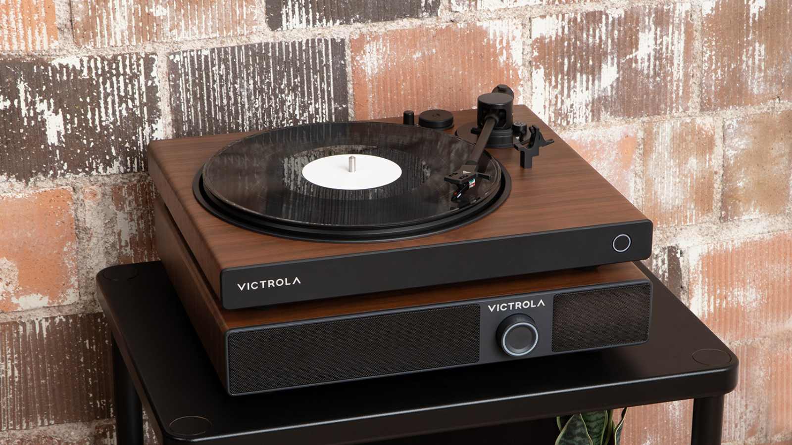 The Victrola soundstage under a Victrola turntable, on a table near a brick wall.