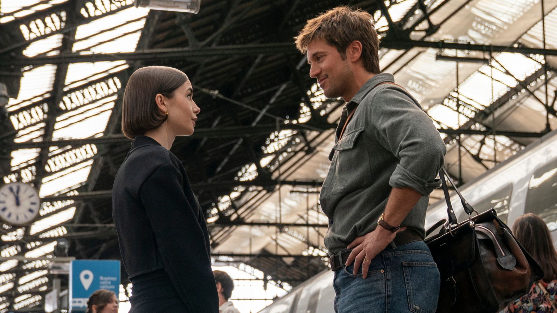 Emily and Gabriel chat on a train platform