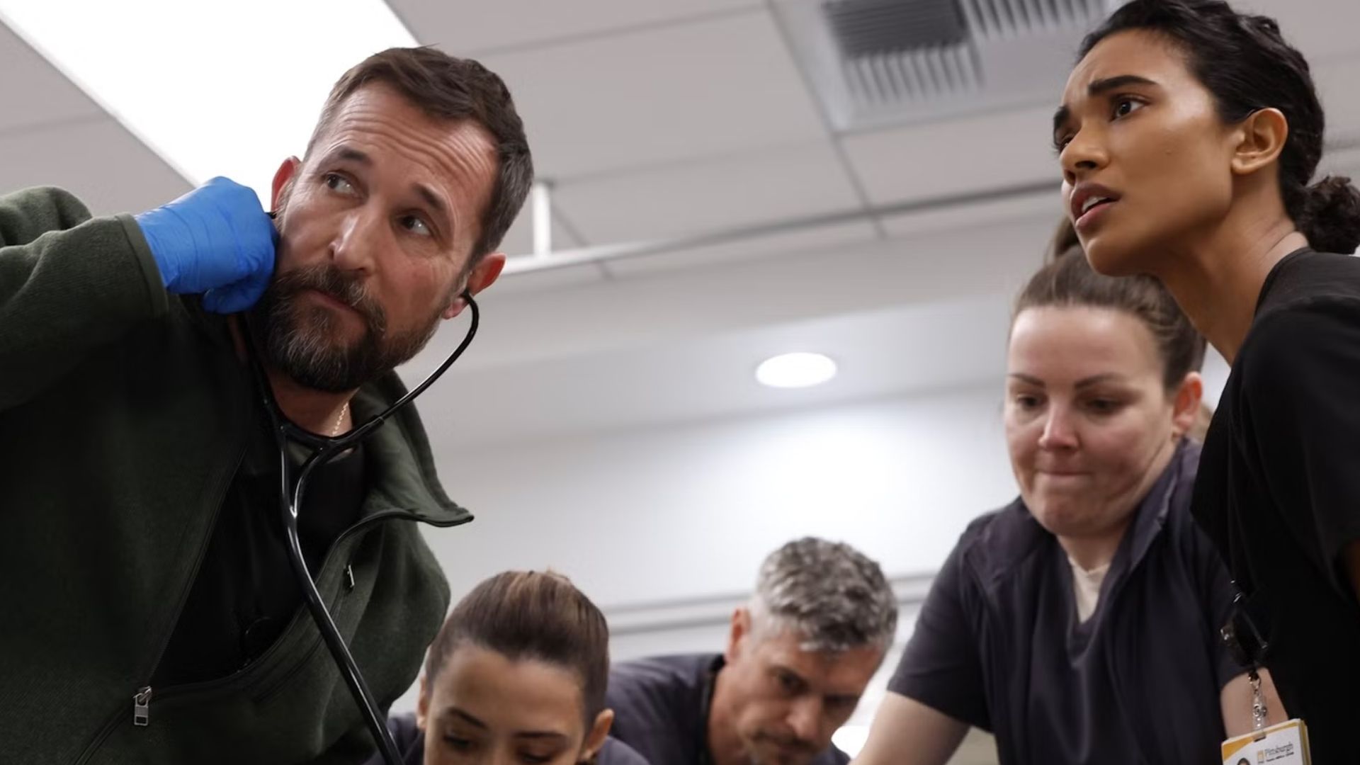 A team of doctors crowds around an operating table