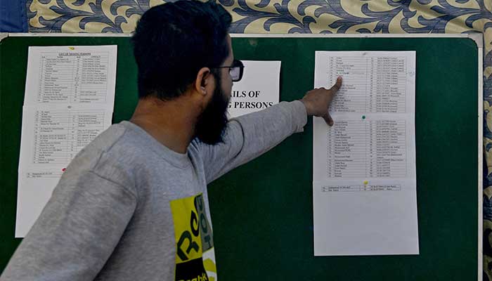 A man checks a list looking for the name of a missing relative following a massive fire that broke out at a shopping mall in Karachi on January 20, 2026. — AFP