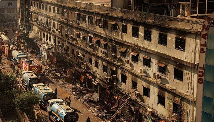 Firefighters walk past the site, following a massive fire that broke out at the Gul Plaza shopping center in Karachi on January 20, 2026. — Reuters