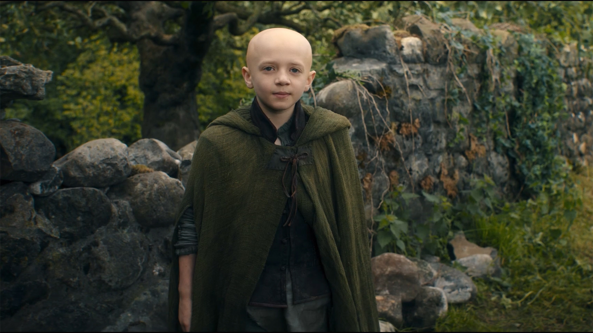 Egg wearing a green cape and smiling while watching a Dunk off-camera in the season 1 finale of A Knight of the Seven Kingdoms.