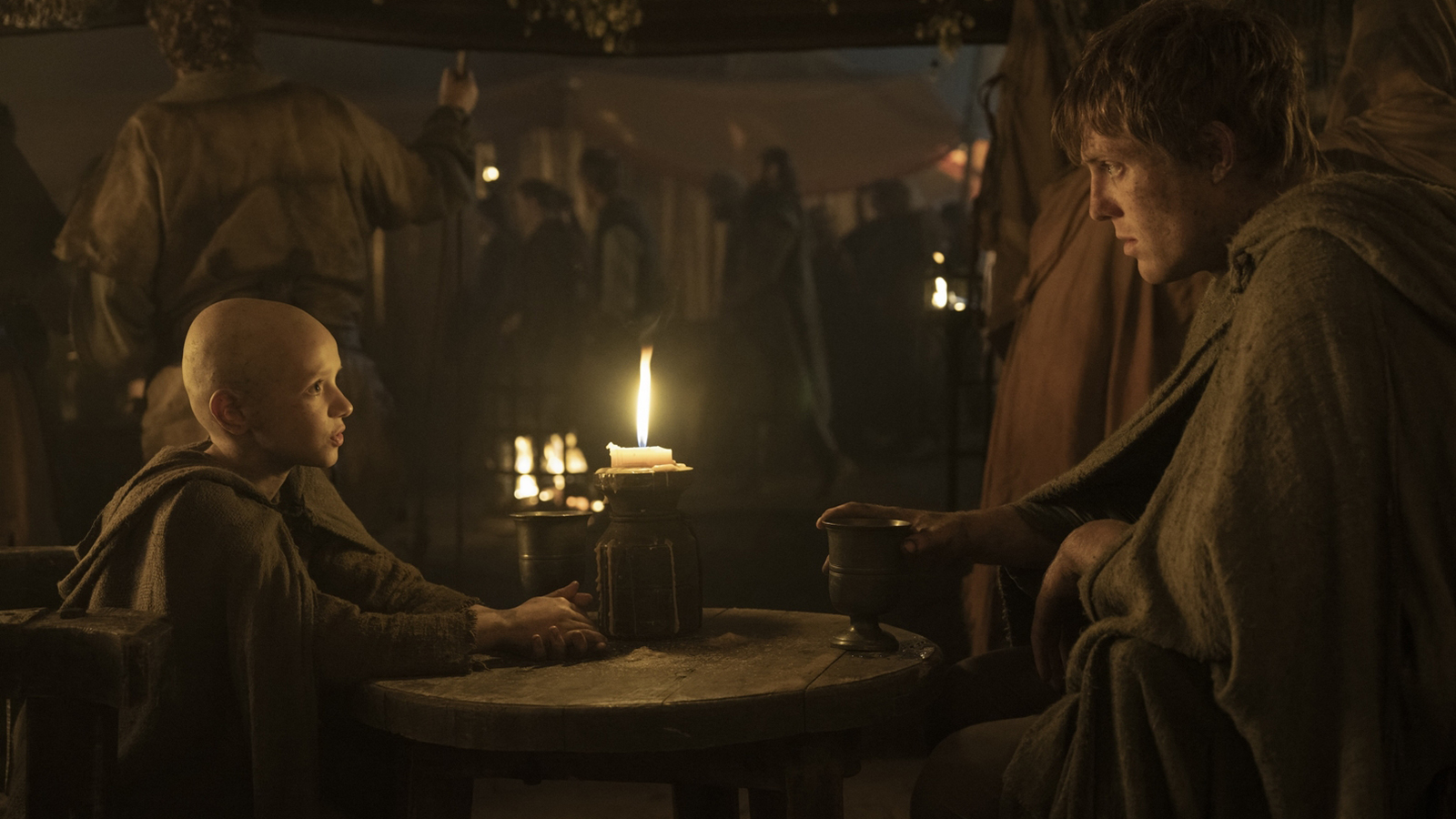 Egg and Dunk sitting at a table in a candlelit tent in A Knight of the Seven Kingdoms