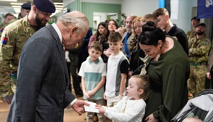 King Charles enjoys a tender moment with a young girl at the barracks