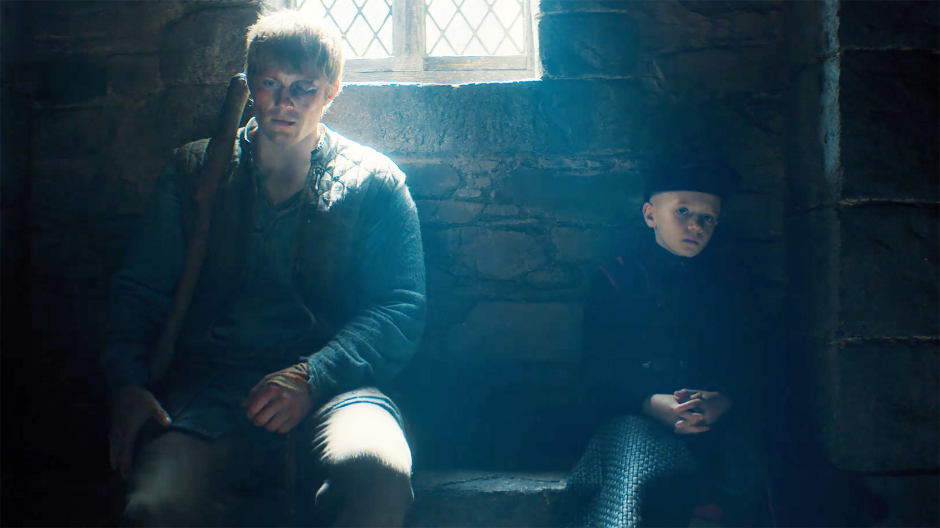 Dunk and Egg sit on a bench inside a building as light streams in through a window in Episode 6 of A Knight of the Seven Kingdoms.