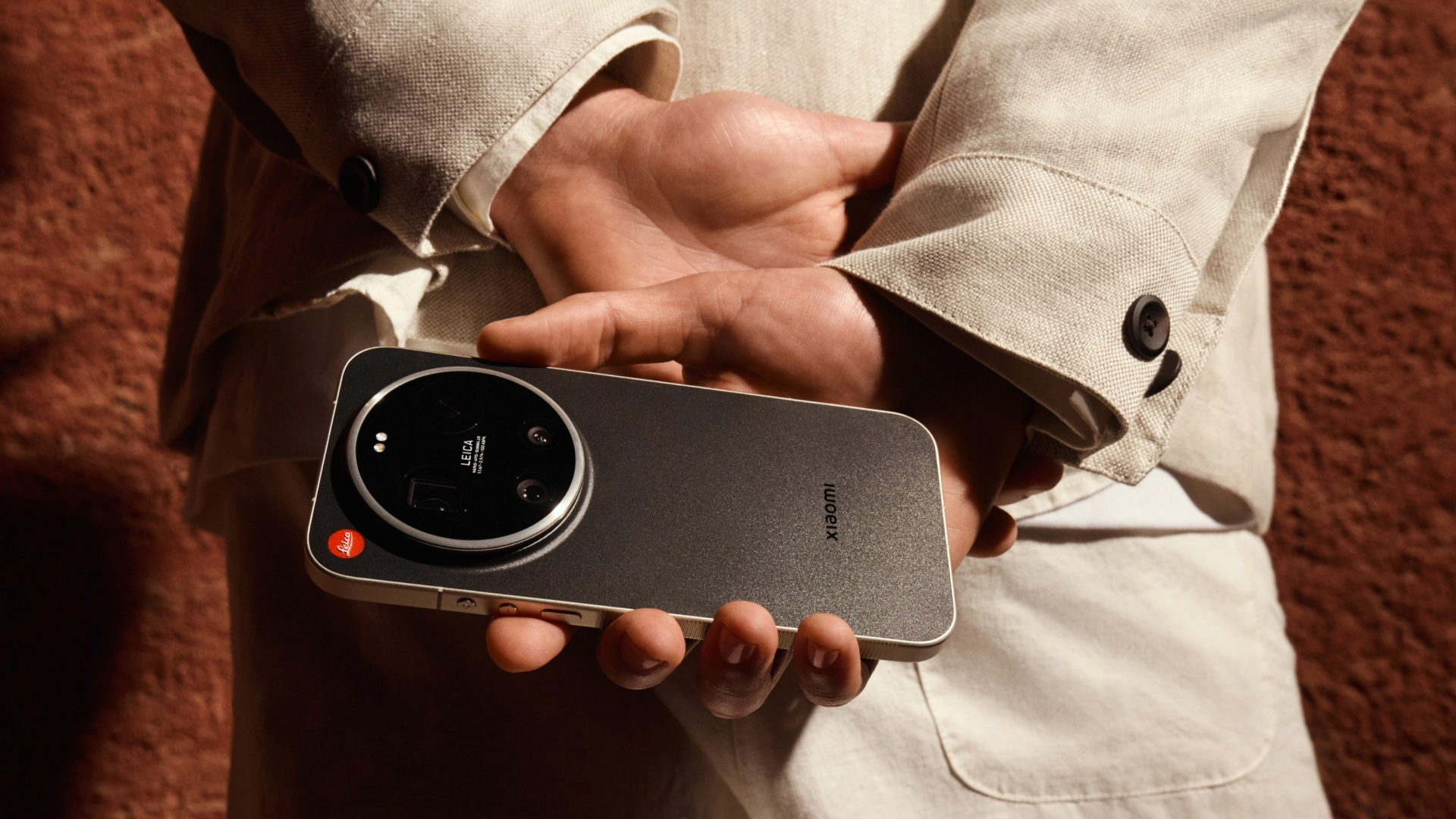 Leica Leitzphone in user's hands, behind his back, with dark red concrete wall background