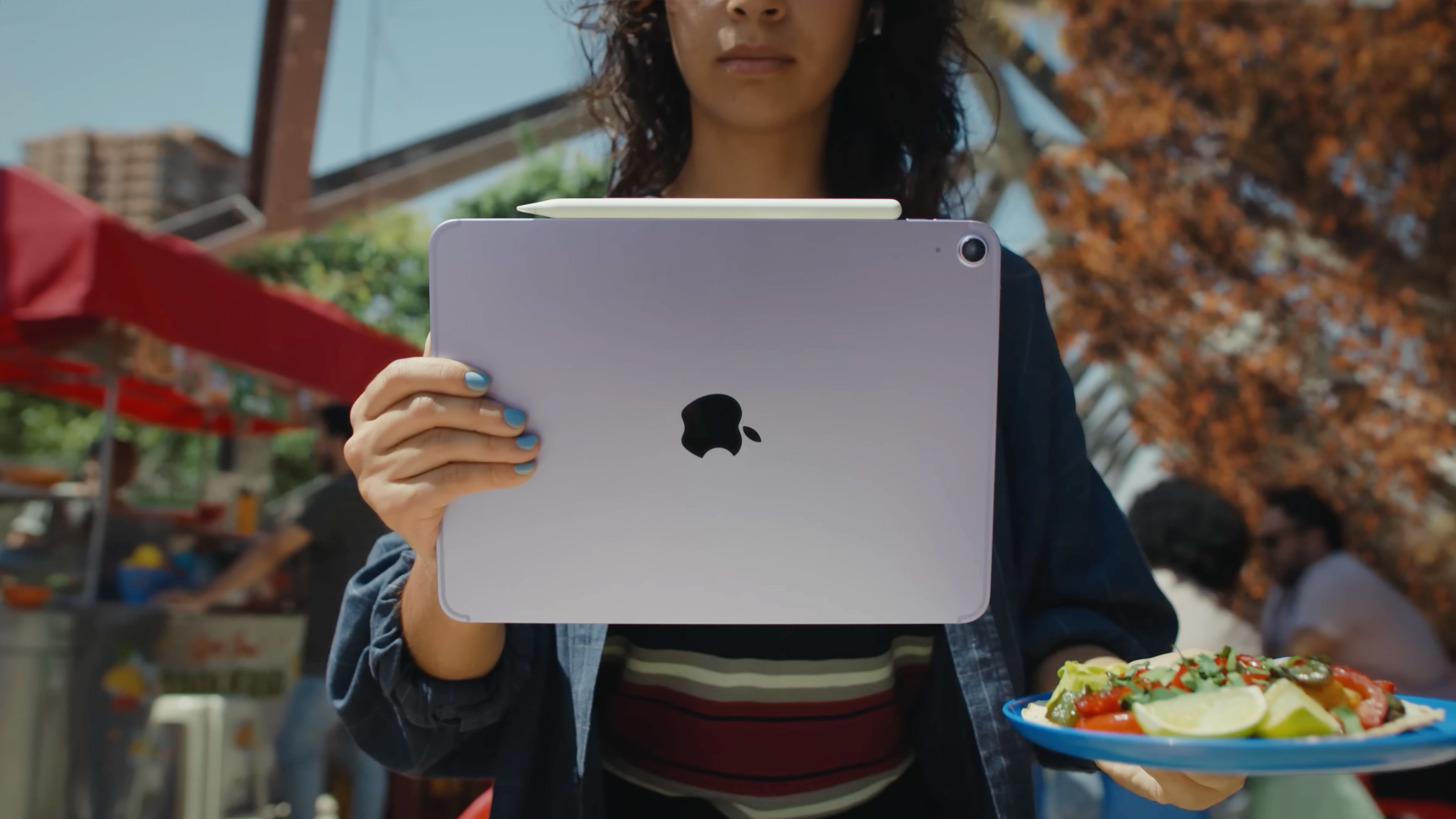 A woman holding the Apple iPad Air M4 with an Apple Pencil on top