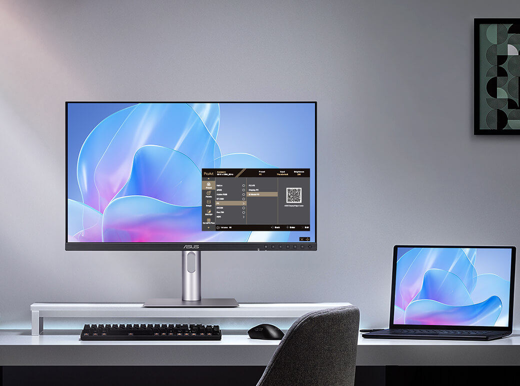 The Asus ProArt PA27JCV monitor placed on a desk next to a laptop