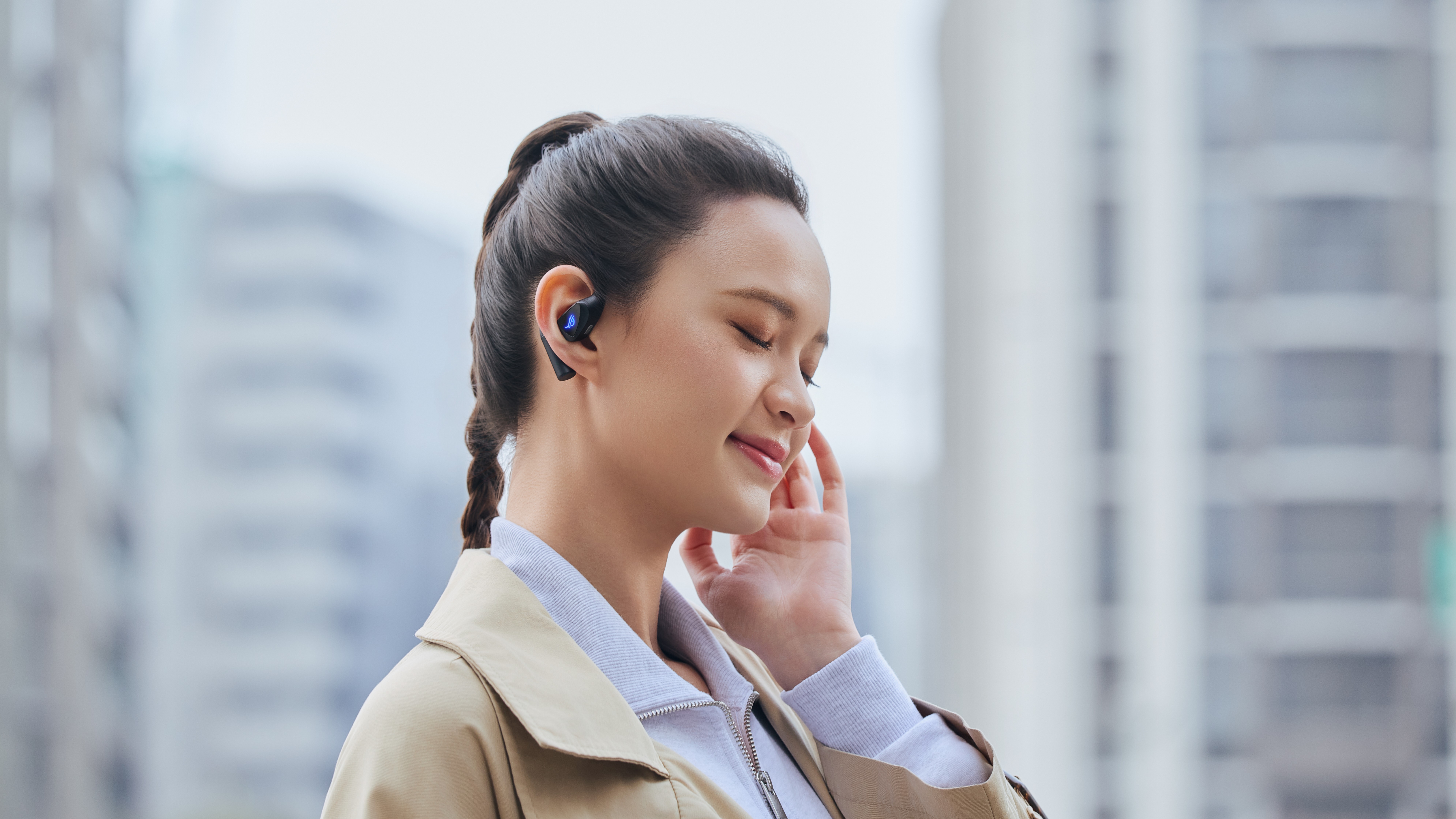 A woman using the new Asus ROG Cetra Open wireless earbuds to listen to music in a city.