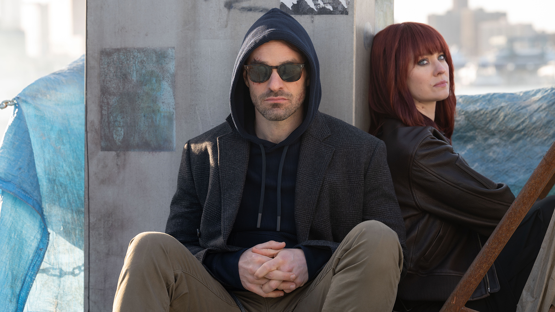 Matt wears sunglasses and his hoodie up and a redhead Karen sitting next to each other in Daredevil: Born Again season 2
