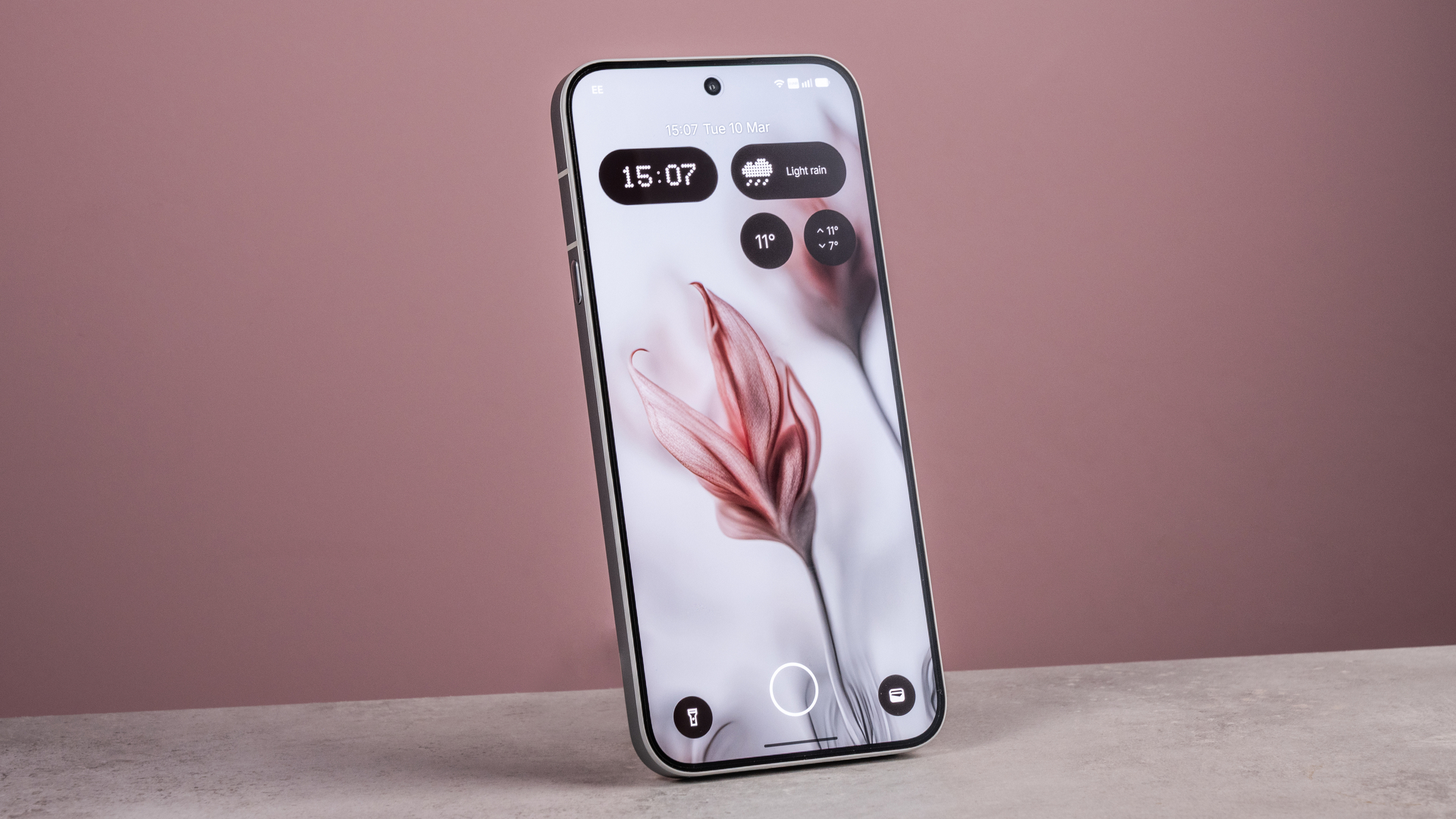 The Nothing Phone (4a) Pro's home screen features an AI image of flowers, in front of a pink background.