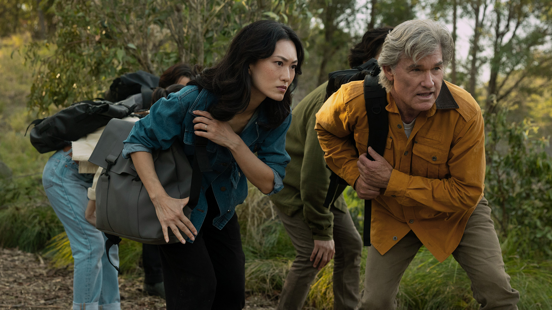 Keiko and Lee carrying backpacks and leaning in a forest in Monarch: Legacy of Monsters season 2 episode 5