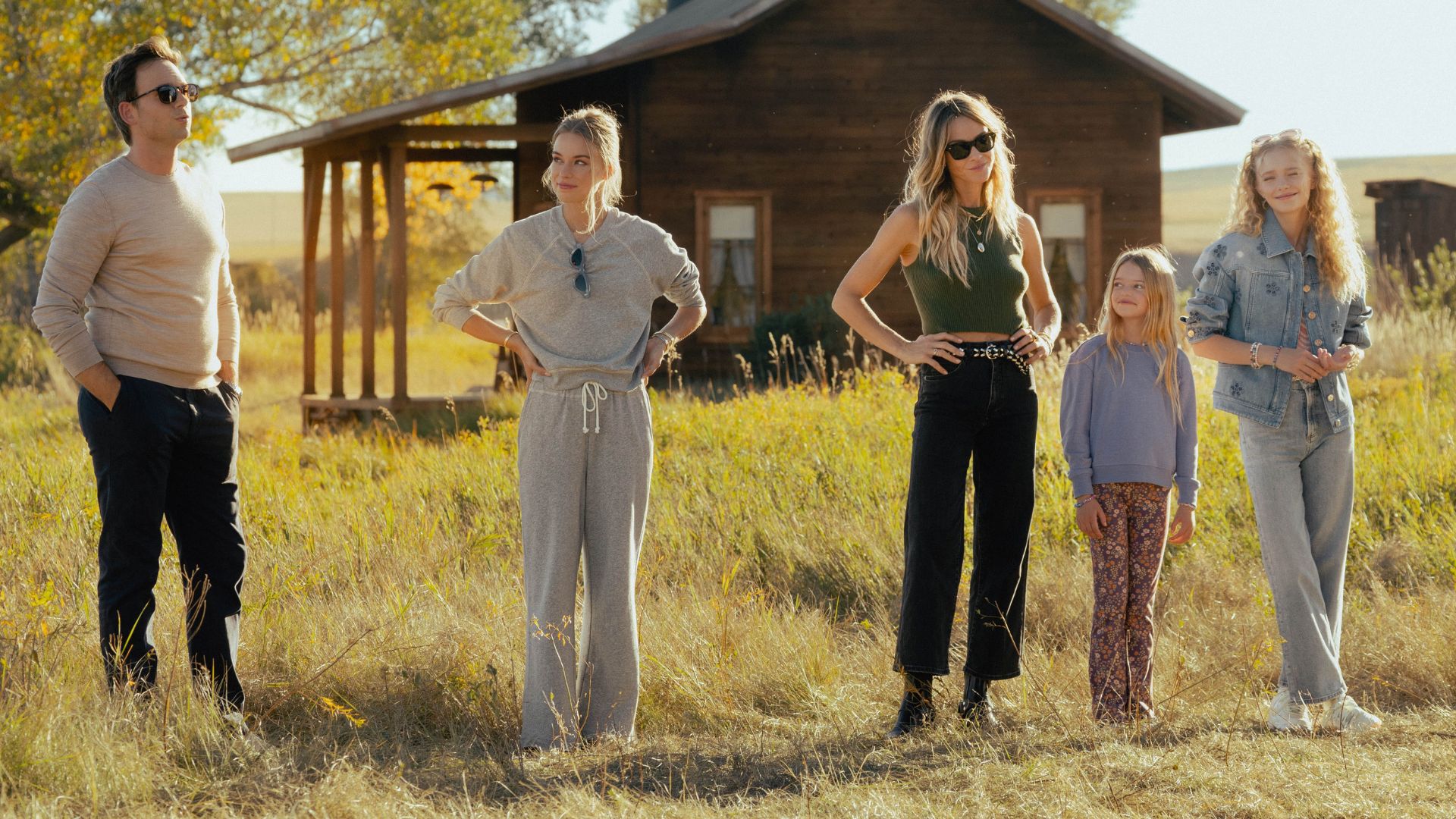 A line of people stands in a field with their hands on their hips