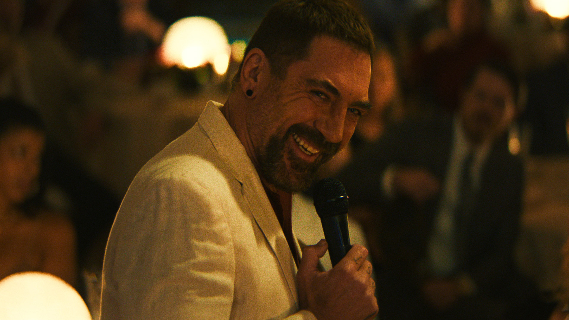 Javier Bardem smiles while holding a microphone as Max Cady in Apple TV's Cape Fear remake