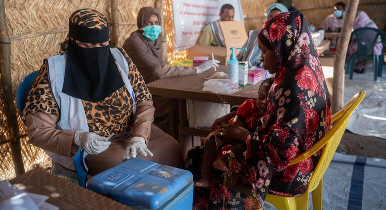 A woman holds a child in her arms as she receives medical treatment at a UNICEF-supported health center in Sudan's Kordofan region, where families have fled violence.