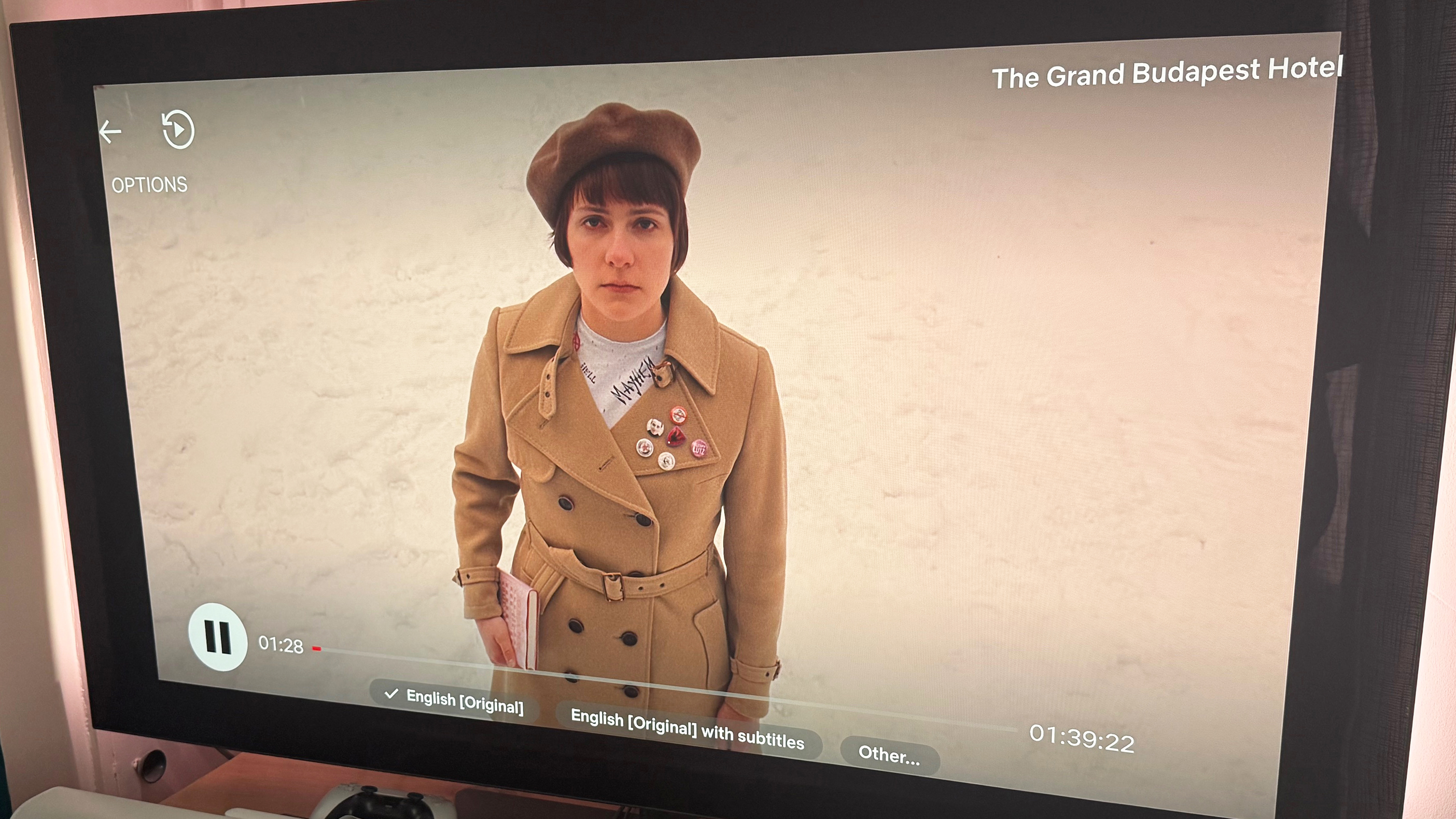 An image of the Grand Budapest Hotel, showing a figure on a snow-covered ground. The new Netflix interface is superimposed on the image