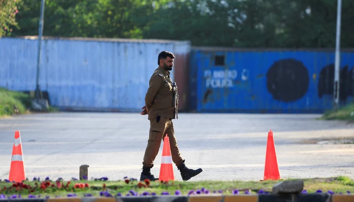 A policeman guards a road blocked by shipping containers, for security measures, at D Chowk, near the President's House, as Pakistan prepares to host the United States and Iran for the second phase of peace talks in Islamabad, April 20, 2026. — Reuters