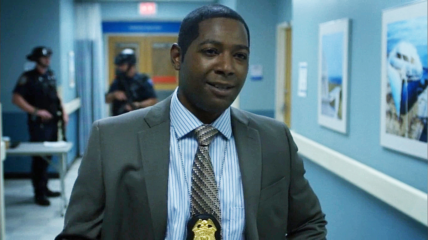 Brett Mahoney wearing a suit and his NYPD badge around his neck in the Netflix television series Daredevil