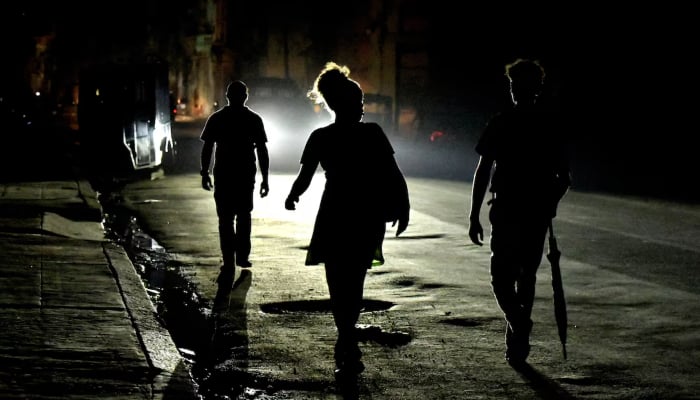 People walk on the street at night as Cuba is hit by an island-wide power outage, in Havana, Cuba, October 18, 2024. — Reuters